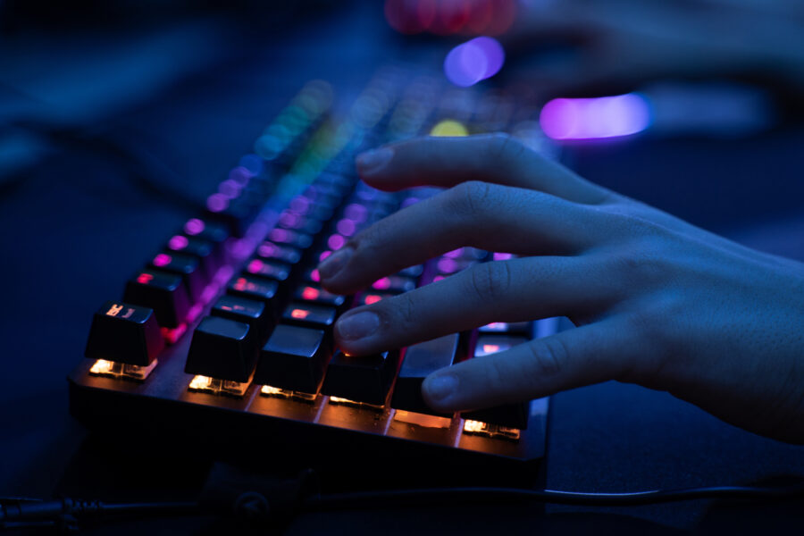 Close up view of the cyber sport gamer holding hand at the computer keyboard while playing at the online games. Stock photo